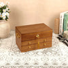 A three-tier wooden jewelry box with a lock and drawers, featuring a brown natural wood finish and gold-colored hardware, placed on a lace tablecloth.