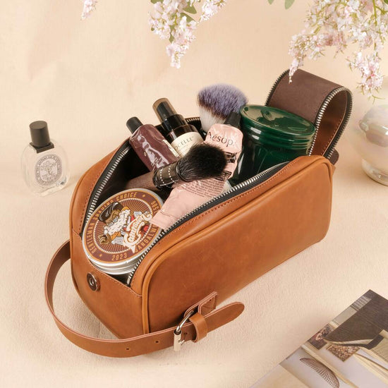 Brown leather toiletry bag with cosmetic items on a light background