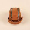Brown leather crossbody bag with zippers on a beige background