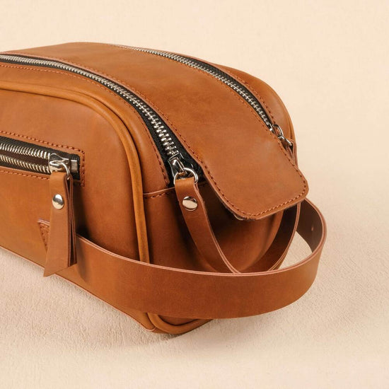 Brown leather bag with zippers on a beige background