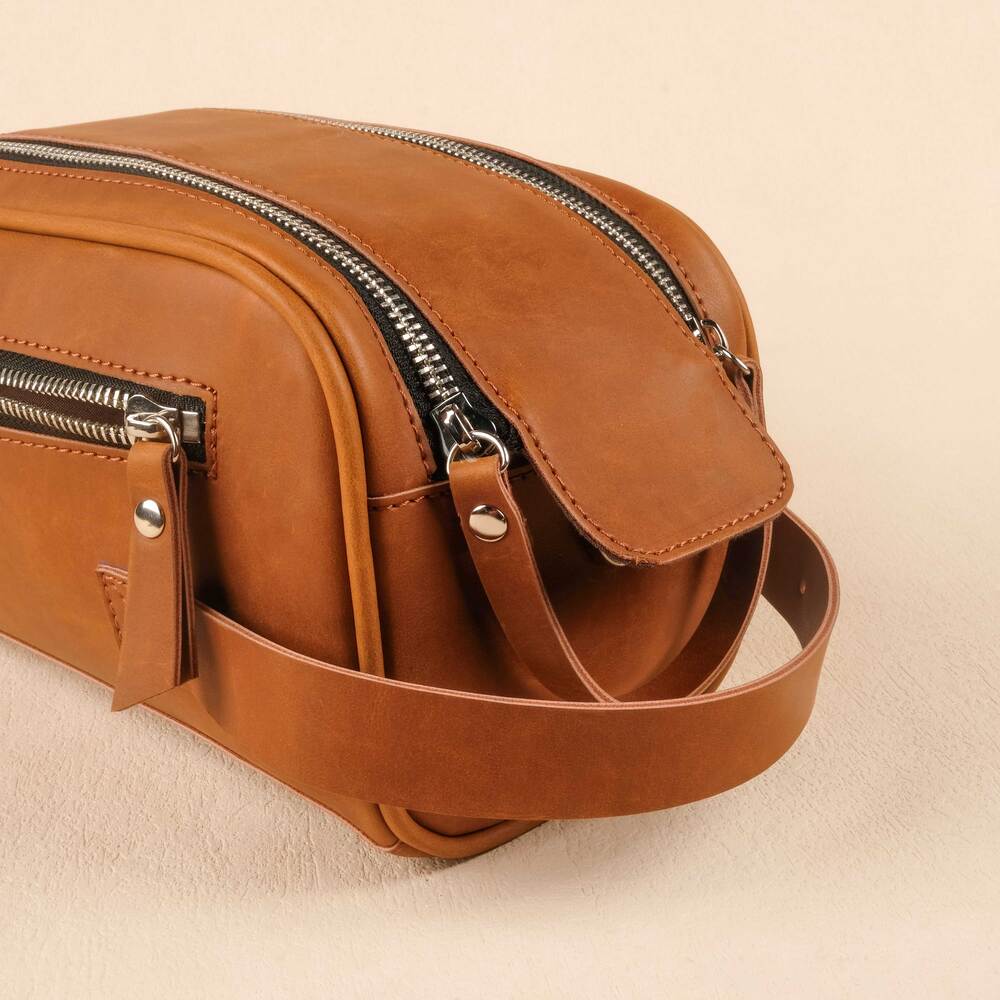 Brown leather bag with zippers on a beige background