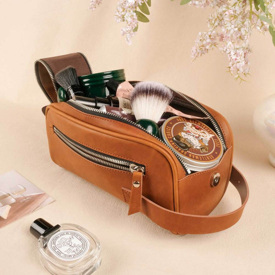 Brown leather toiletry bag with cosmetic items on a beige background