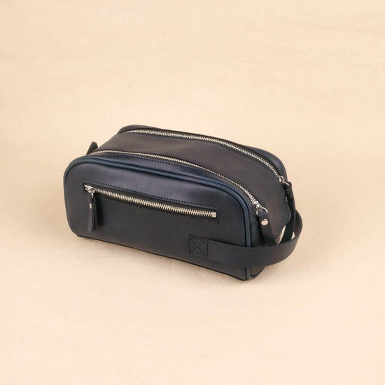 Navy blue toiletry bag with zippers on a beige background
