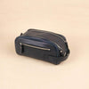 Navy blue toiletry bag with zippers on a beige background
