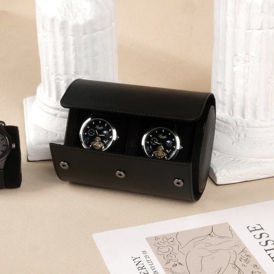 Black watch winder with two watches on a beige surface with a white textured background