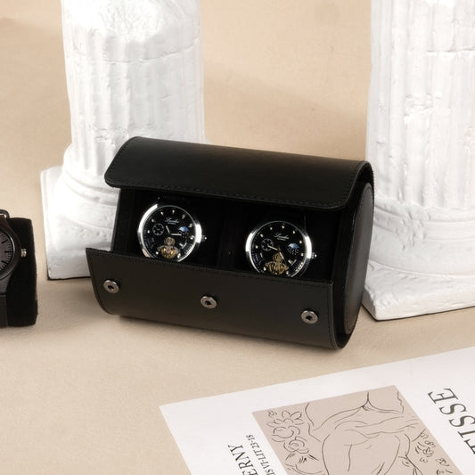 Black watch winder with two watches on a beige surface with a white textured background