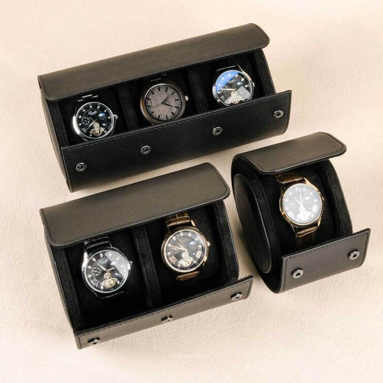 Set of black watch display cases with watches inside on a beige background