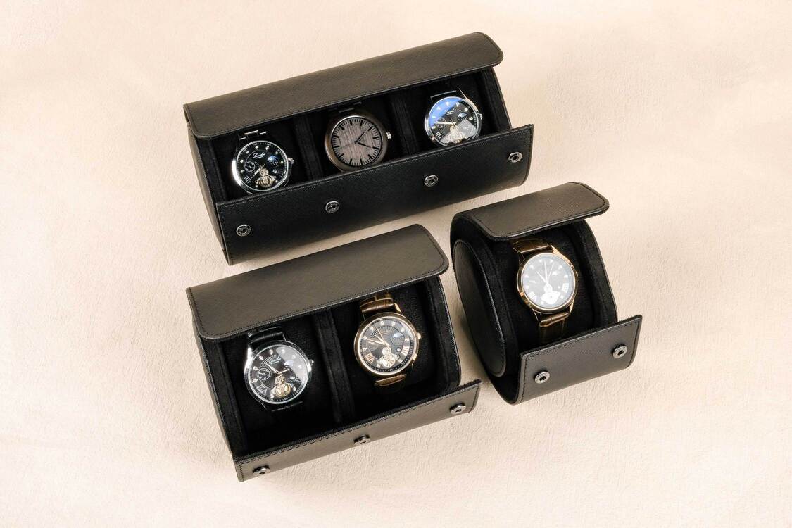 Set of black watch display cases with watches inside on a beige background