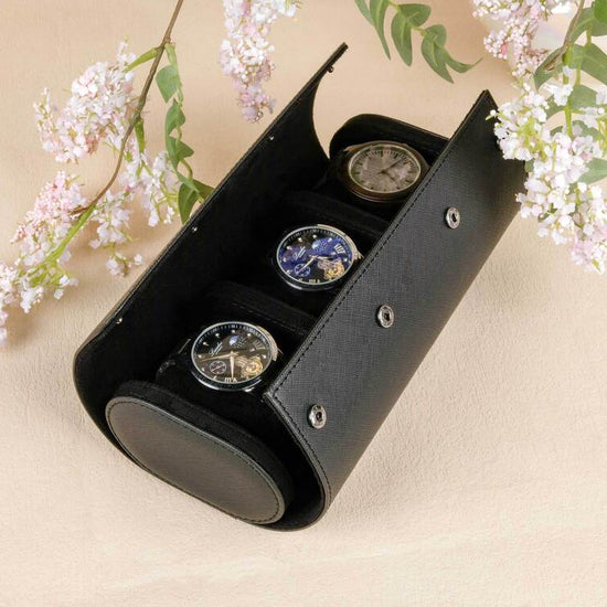 Black jewelry box with three round items on a beige background with floral elements