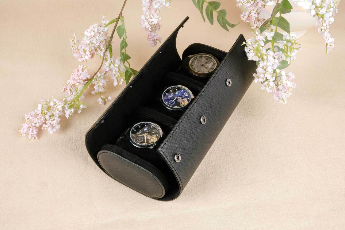 Black jewelry box with three round items on a beige background with floral elements