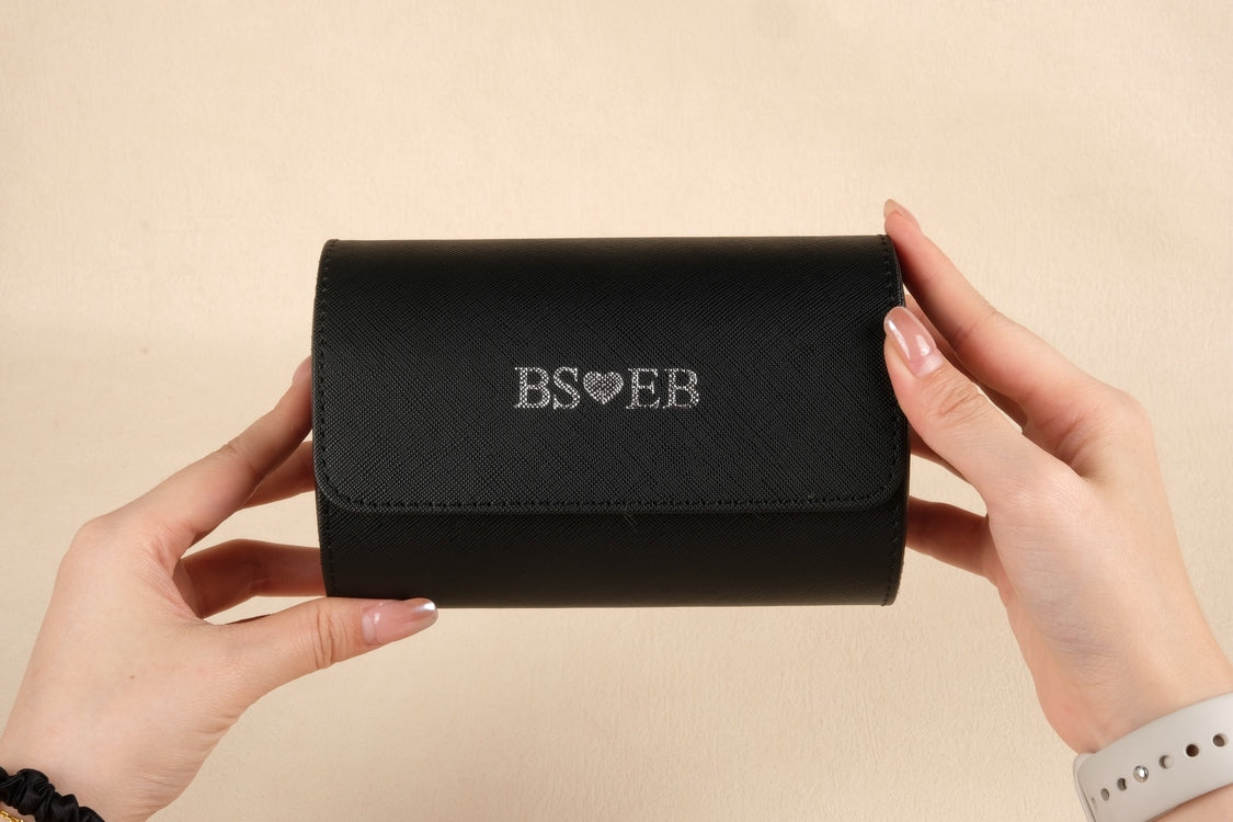 Black wallet held by hands with 'BS❤️EB' branding on a beige background