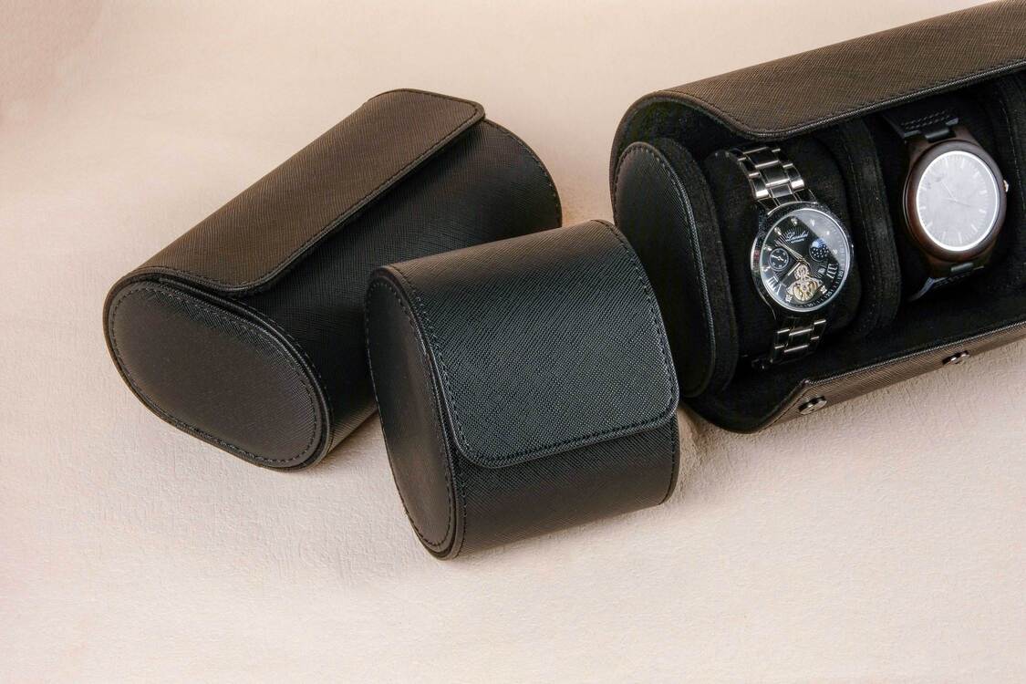 Black watch case with two watches on a beige background