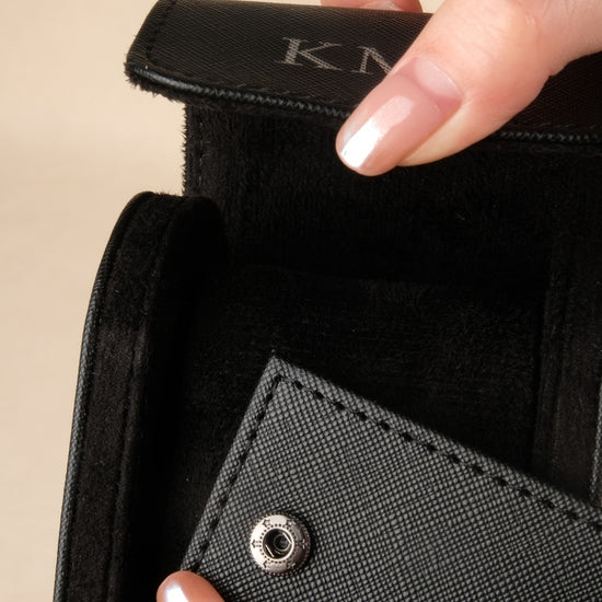 Close-up of a person holding a black wallet with 'KIM' branding.