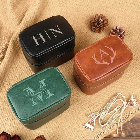 Three jewelry boxes with initials on a textured surface with decorative elements.
