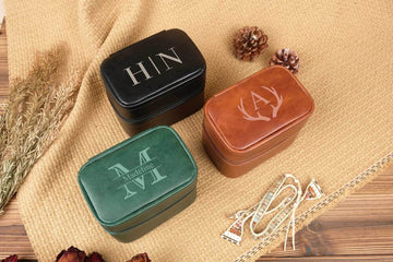 Three jewelry boxes with initials on a textured surface with decorative elements.