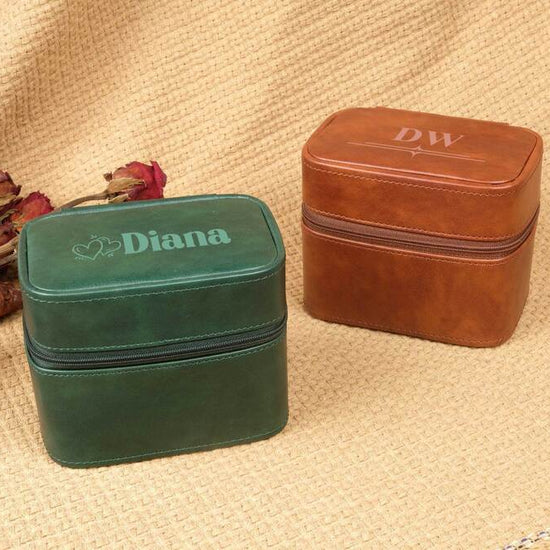 Two jewelry boxes, one green and one brown, on a textured surface with dried flowers.