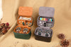 Two jewelry cases, one open with watches and accessories, the other closed, on a textured surface.