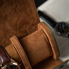 Brown leather watch case with a watch inside, on a blurred background